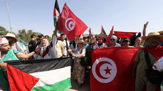 Des militants, qui se dirigent vers Gaza par voie terrestre pour briser le siège du territoire meurtri par la guerre, brandissent les drapeaux palestinien et tunisien à leur arrivée à Zawiyah, à environ 45 kilomètres à l'ouest de la capitale libyenne, Tripoli, le 10 juin 2025. Des centaines de personnes, principalement des Tunisiens, dans un convoi de neuf bus comprenant des médecins à destination de Gaza, ont rejoint le convoi "Soumoud", qui signifie "constance" en arabe, dans le but d'atteindre Rafah, dans le sud de Gaza, à la frontière avec l'Egypte, "d'ici la fin de la semaine", ont indiqué des militants à l'AFP.