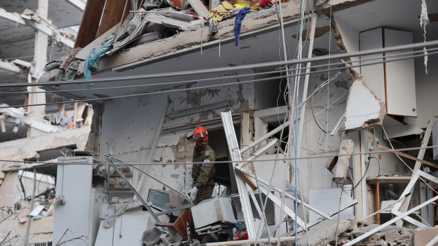 Un secouriste travaille dans un bâtiment endommagé à la suite d'un tir de missile iranien dans la ville israélienne de Bat Yam, au sud de Tel Aviv, le 15 juin 2025. Des sirènes de raids aériens et des explosions ont retenti à Jérusalem et à Tel Aviv tôt le 15 juin, ont constaté des journalistes de l'AFP, alors qu'Israël et l'Iran ont échangé des tirs pour la troisième journée.