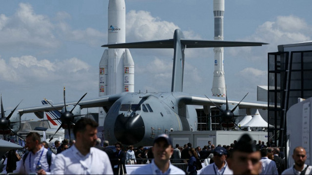 Cette photographie montre un avion militaire Airbus A400M Grizzly - 0134 avec des avions et des fusées spatiales Ariane 1 (R) et Ariane 5 ECA en arrière-plan lors de la 55e édition du Salon international de l'aéronautique et de l'espace à l'aéroport de Paris-Le Bourget, au Bourget, dans la banlieue de Paris, le 16 juin 2025.