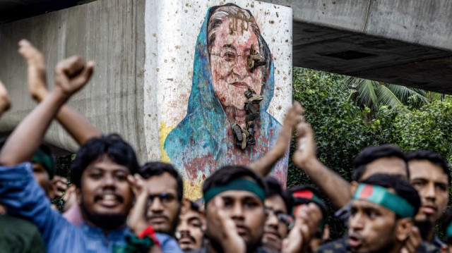 Des étudiants scandent des slogans près d'une peinture murale vandalisée de la première ministre du Bangladesh, Sheikh Hasina, lors d'une manifestation réclamant des comptes et un procès contre Hasina, près de l'université de Dhaka, dans la capitale, le 12 août 2024.