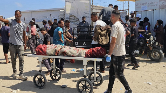 Un Palestinien transporte un corps enveloppé à l'extérieur d'un hôpital à Rafah, dans le sud de la bande de Gaza, le 16 juin 2025.