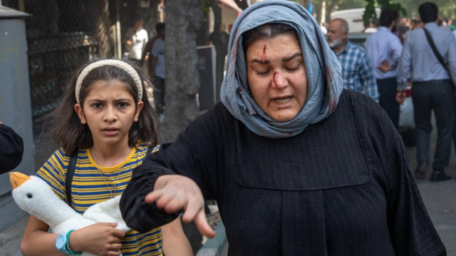 Une femme iranienne blessée réagit après une frappe israélienne sur le boulevard Keshavarz, dans le centre de Téhéran, le 15 juin 2025.