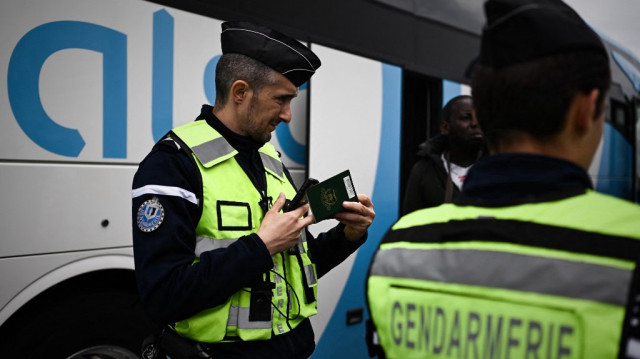 Un gendarme français vérifie le passeport d'un passager d'un bus commercial lors d'un contrôle routier des bus commerciaux à un péage autoroutier, dans le cadre d'une opération nationale visant l'immigration illégale et clandestine à Virsac, à 30 km au nord de Bordeaux, dans le sud-ouest de la France, le 20 mai 2025.