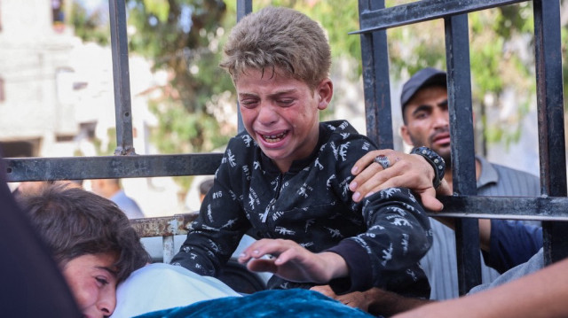 Des garçons se recueillent devant le corps d'un Palestinien tué la veille par des tirs israéliens alors qu'il cherchait de l'aide alimentaire, lors de ses funérailles à l'hôpital Al-Shifa de la ville de Gaza, le 18 juin 2025.