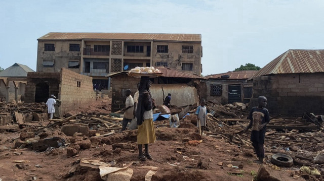 Une femme se tient à côté de débris de bâtiments endommagés à Mokwa le 1er juin 2025, après que la ville ait été frappée par des pluies torrentielles dans la nuit de mercredi à jeudi. Les inondations ont provoqué le déplacement de plus de 3 000 personnes.