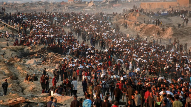 Des personnes portant des sacs de farine marchent dans la rue al-Rashid à l'ouest de Jabalia le 17 juin 2025, après que des camions d'aide humanitaire soient entrés dans le nord de la bande de Gaza par le poste frontière de Zikim contrôlé par Israël.