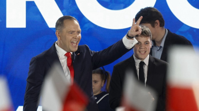 Karol Nawrocki, candidat à l'élection présidentielle polonaise de 2025 soutenu par le parti de droite polonais Droit et Justice (PiS), fait clignoter le signe de la victoire devant ses partisans alors que les sondages de sortie des urnes sont annoncés à la télévision lors de leur soirée électorale au théâtre Mala Warszawa à Varsovie, en Pologne, lors du second tour des élections présidentielles, le 1er juin 2025.