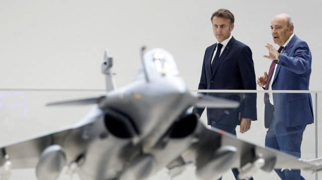 Le président français Emmanuel Macron (G) écoute Eric Trappier, président-directeur général de Dassault Aviation, alors qu'ils regardent la maquette d'un avion de combat Rafale sur le stand du constructeur aéronautique Dassault Aviation lors d'une visite à la 55e édition du Salon international de l'aéronautique et de l'espace (SIAE) à l'aéroport de Paris-Le Bourget, au Bourget, au nord de Paris, le 20 juin 2025.