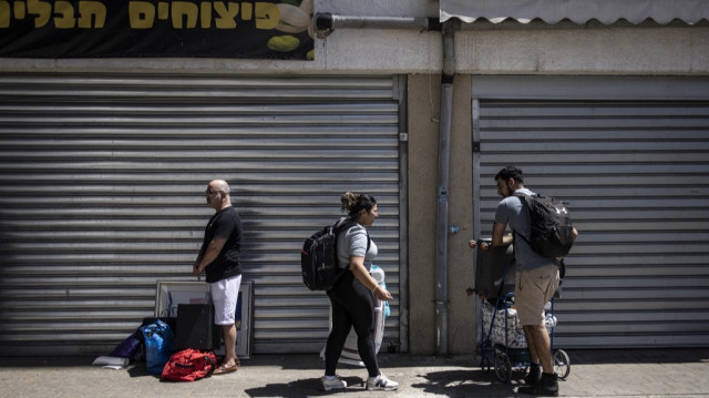 Des personnes marchent avec leurs affaires alors qu'elles évacuent leurs maisons endommagées, un jour après qu'un missile iranien ait frappé une zone, à Holon dans le centre d'Israël près de Tel Aviv, le 20 juin 2025.