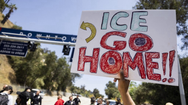Un manifestant brandit une pancarte sur laquelle on peut lire "ICE rentrez chez vous" devant l’une des entrées du parking du Dodger Stadium, où des agents fédéraux de l’immigration se sont vu refuser l’accès, à Los Angeles, en Californie, le 19 juin 2025.