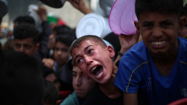 Des enfants palestiniens attendent de la nourriture à un point de distribution à Nuseirat, dans le centre de la bande de Gaza, le 11 juin 2025.
