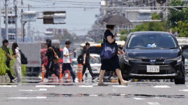 Des personnes traversent une rue sous un soleil de plomb à Tokyo le 20 juin 2025.