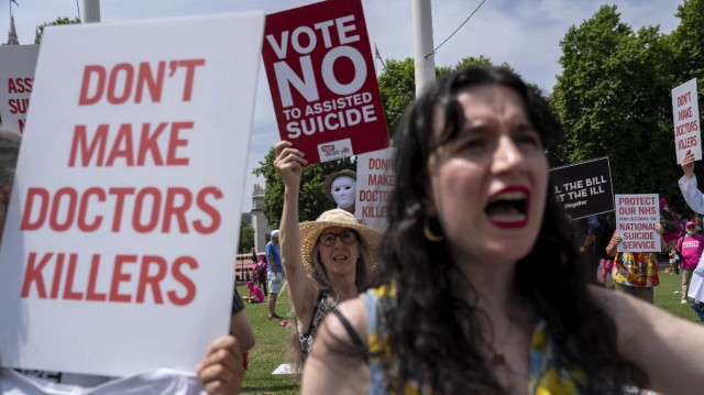 Des manifestants opposés à une modification de la loi sur l'aide à mourir brandissent des pancartes lors d'une manifestation devant le Palais de Westminster, qui abrite les Chambres du Parlement, au centre de Londres, le 20 juin 2025, alors que les députés procèdent à un vote à couteaux tirés sur l'autorisation de l'aide à mourir pour les malades en phase terminale.