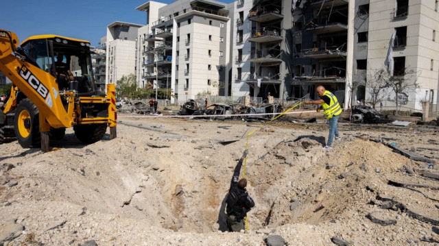 Des membres des forces de sécurité israéliennes examinent un cratère au sol sur le site d'une attaque de missiles iraniens dans un quartier résidentiel de Beersheba, dans le sud d'Israël, le 20 juin 2025.