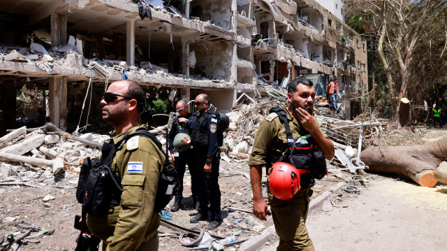 Les forces de sécurité israéliennes et les premiers intervenants se rassemblent devant un bâtiment lourdement endommagé par une frappe iranienne à Tel Aviv, le 22 juin 2025. Au moins 16 personnes ont été blessées et au moins un impact a été signalé dans le centre d'Israël après que l'Iran a lancé deux vagues de missiles sur le pays à la suite du bombardement de ses sites nucléaires par les États-Unis, selon les services de secours et les rapports.