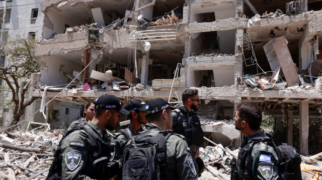 Des policiers israéliens se rassemblent devant un bâtiment touché par une frappe iranienne à Tel Aviv le 22 juin 2025. Au moins 16 personnes ont été blessées et au moins un impact a été signalé dans le centre d'Israël après que l'Iran a lancé deux vagues de missiles sur le pays à la suite du bombardement de ses sites nucléaires par les États-Unis, selon les services de secours et les rapports.