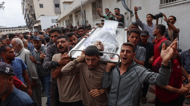 Des Palestiniens portent le corps d'un homme tué la veille alors qu'il tentait d'obtenir de l'aide à un point de distribution près du poste frontière de Zikim contrôlé par Israël, lors d'une procession funéraire à l'hôpital Al-Shifa dans la ville de Gaza, le 23 juin 2025.