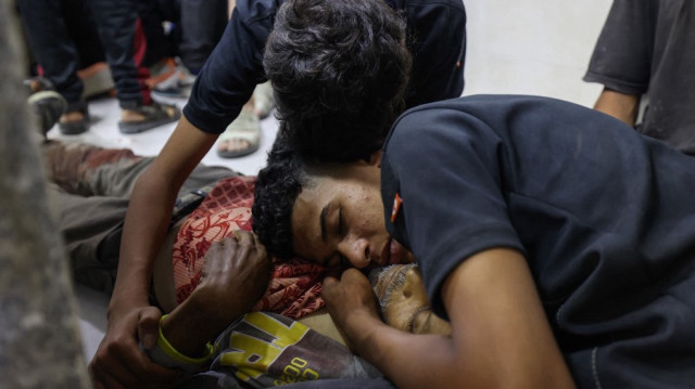 Des jeunes Palestiniens se recueillent devant le corps d'un proche tué par des tirs israéliens au point de distribution d'aide alimentaire mis en place par la Fondation humanitaire de Gaza (GHF) sur la route de Salaheddin, à l'hôpital Al-Awda dans le camp de réfugiés de Nuseirat, dans le centre de la bande de Gaza, le 24 juin 2025.