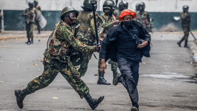 Un manifestant grimace lorsqu'un membre des forces de sécurité kenyanes le frappe avec une matraque dans le centre de Nairobi, le 25 juin 2025, lors d'une journée de protestation prévue pour marquer le premier anniversaire de la prise d'assaut du parlement.