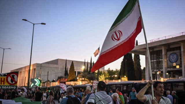 Un manifestant brandit un drapeau iranien lors d'une manifestation dans le centre d'Athènes en soutien au peuple palestinien et contre les attaques américaines en Iran, le 23 juin 2025. Quelque 10 000 manifestants ont marché jusqu'à l'ambassade américaine.