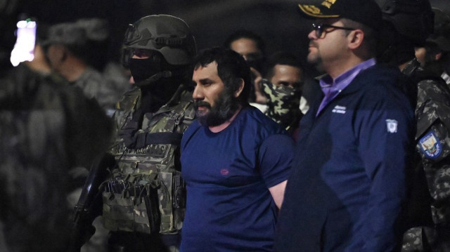 Le trafiquant de drogue Adolfo Macias, alias Fito, est gardé par le ministre de l'intérieur équatorien John Reimberg (à droite) et du personnel militaire à son arrivée à la base aérienne de Guayaquil, en Équateur, le 25 juin 2025, après sa capture à Manta, dans la province de Manabi.