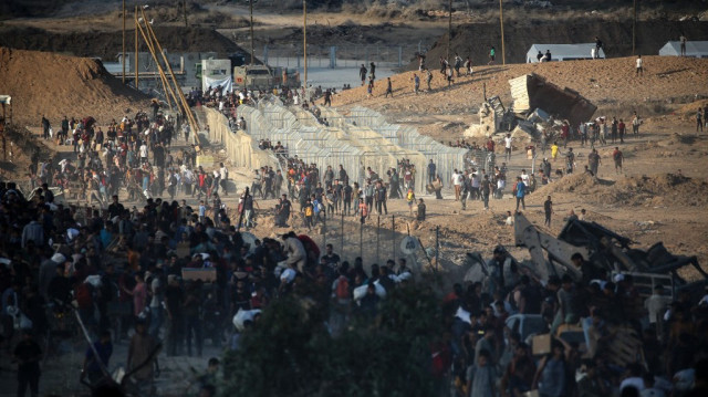 Des Palestiniens se rassemblent à un point de distribution d'aide mis en place par la Fondation humanitaire de Gaza (GHF), près du camp de réfugiés de Nuseirat, dans le centre de la bande de Gaza, le 25 juin 2025.