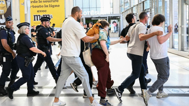 Des policiers évacuent par la force des manifestants lors d'une visite du ministre français de l'Intérieur à la gare du Nord à Paris, le 19 juin 2025, alors que la France lance une opération de deux jours de contrôles dans les gares, les trains et les bus pour lutter contre "l'immigration clandestine".