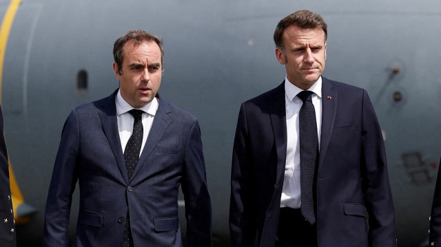 Le président français Emmanuel Macron (à droite) marche sur le tarmac avec le ministre français des Armées Sébastien Lecornu après avoir débarqué d'un avion militaire Airbus A400M lors d'une visite à la 55e édition du Salon international de l'aéronautique et de l'espace (SIAE) à l'aéroport de Paris-Le Bourget, au Bourget, au nord de Paris, le 20 juin 2025.