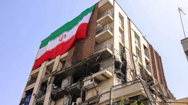 Cette photo montre un immeuble résidentiel touché par une frappe israélienne, recouvert d'un grand drapeau iranien, à Téhéran, le 25 juin 2025. Un fragile cessez-le-feu dans la guerre Iran-Israël semblait tenir le 25 juin, après 12 jours de frappes qui ont vu Israël et les États-Unis pilonner les installations nucléaires de la république islamique.