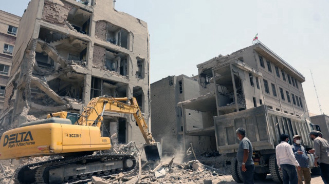 Une pelleteuse est utilisée pour déblayer les décombres devant un bâtiment récemment touché par des frappes israéliennes à Téhéran, le 26 juin 2025, à la suite d'un cessez-le-feu avec Israël qui a mis fin à 12 jours de combats.