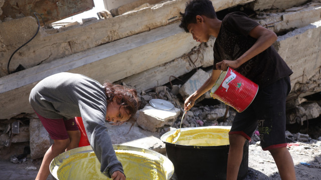 Des enfants palestiniens grattent le pot pour obtenir une portion de nourriture dans un point de distribution alimentaire de la ville de Gaza, le 27 juin 2025. Après plus de 20 mois d'un conflit dévastateur, les groupes de défense des droits de l'homme affirment que la population de Gaza, qui compte plus de deux millions d'habitants, est confrontée à des conditions proches de la famine.