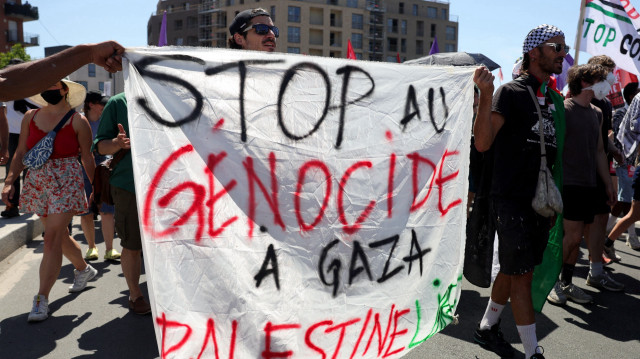 Des manifestants tiennent une pancarte sur laquelle on peut lire "Stop au génocide à Gaza, Palestine libre" lors d'une manifestation appelée par le collectif "War on War" contre "l'économie de guerre" et "le business de la mort" en marge de la 55e édition du Salon international de l'aéronautique et de l'espace (SIAE) à l'aéroport Paris-Le Bourget, à Bobigny, en banlieue parisienne, le 21 juin 2025.