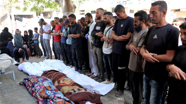 Des Palestiniens prient devant les corps de leurs proches tués lors des frappes israéliennes de la nuit, dans l'enceinte de l'hôpital Al-Shifa, dans le centre de la bande de Gaza, le 28 juin 2025.