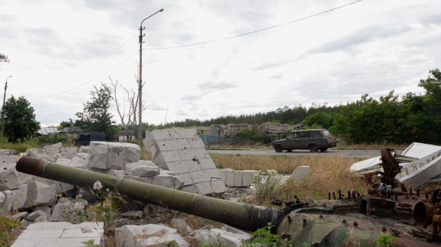 Une voiture passe devant un char partiellement brûlé dans la ville de Svyatohirs'k, dans la région de Donetsk, le 26 juin 2025, lors de l'invasion russe de l'Ukraine.