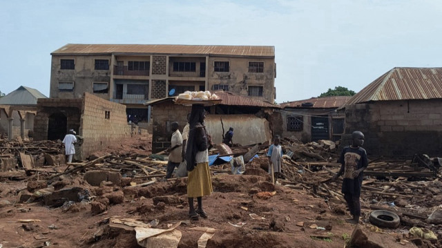 Une femme se tient à côté de débris de bâtiments endommagés à Mokwa le 1er juin 2025, après que la ville ait été frappée par des pluies torrentielles dans la nuit de mercredi à jeudi. Les inondations ont provoqué le déplacement de plus de 3 000 personnes.
