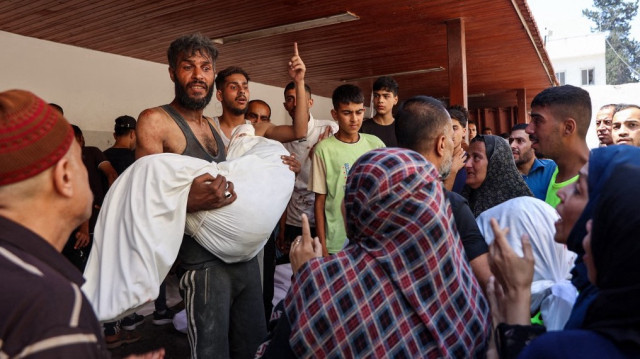 Un Palestinien porte le corps d'une personne tuée lors d'une frappe israélienne sur un entrepôt de distribution d'aide humanitaire dans le quartier de Sabra, dans la ville de Gaza, au centre de la bande de Gaza, dans l'enceinte de l'hôpital arabe Al-Ahli, également connu sous le nom d'hôpital baptiste, le 30 juin 2025.
