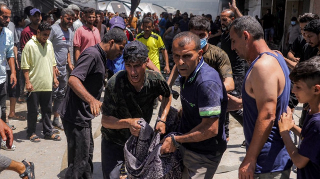Des hommes emportent le corps d'une victime tuée dans un incendie suite à une frappe israélienne à l'école Osama bin Zaid de l'UNRWA dans le district de Saftawi à l'ouest de Jabalia dans le nord de la bande de Gaza, le 27 juin 2025.