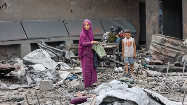 Une femme palestinienne ramasse des objets récupérables dans les décombres de l'école Yaffa, dans le quartier de Tuffah, à Gaza, après les frappes israéliennes de la nuit, le 30 juin 2025, alors que le conflit entre Israël et le mouvement militant islamiste Hamas se poursuit.