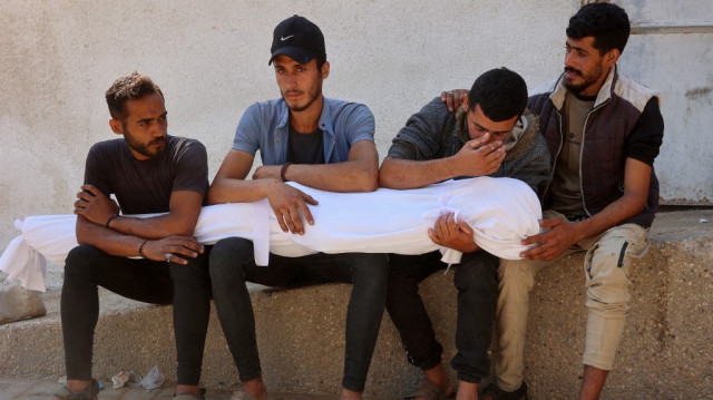Des hommes sont assis alors qu'ils transportent le corps d'une victime qui a été tuée lors d'un bombardement israélien pendant la nuit, lors des funérailles à l'extérieur de l'hôpital al-Shifa dans la ville de Gaza, le 4 juin 2025.