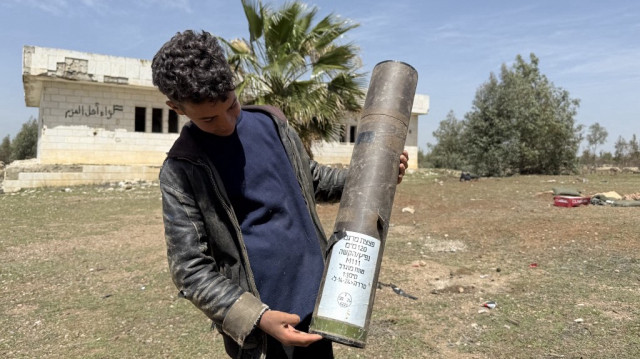 Un garçon tient un tube de munitions vide qui a été laissé par les troupes israéliennes à Horsh Sad Tassil, dans la province méridionale de Daraa, en Syrie, le 3 avril 2025.