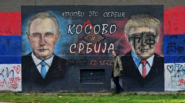 Un passant marche devant une fresque représentant le président russe Vladimir Poutine (à gauche) et le président américain Donald Trump, accompagnée d'une inscription en cyrillique indiquant "Le Kosovo est la Serbie", le 8 novembre 2020, à Belgrade.