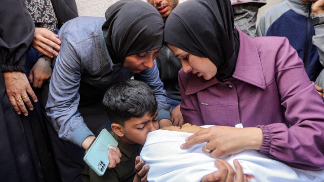 Un garçon embrasse le corps d'une victime tuée lors d'un bombardement israélien nocturne, alors qu'il est porté par une femme avec d'autres personnes en deuil à l'hôpital al-Shifa dans la ville de Gaza, le 4 juin 2025.