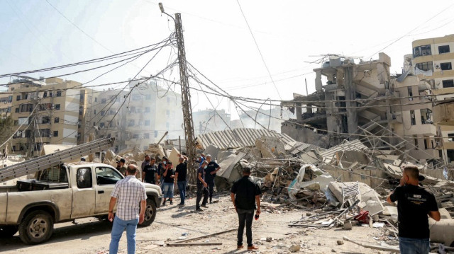 Des personnes se tiennent près des décombres d’un immeuble effondré, sur le site d’une frappe aérienne israélienne menée dans la nuit dans le quartier de Hadath, dans la banlieue sud de Beyrouth, le 6 juin 2025.
