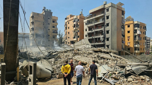 Des hommes se tiennent devant les décombres d'un bâtiment effondré sur le site d'une frappe aérienne israélienne dans le quartier de Kafaat, dans la banlieue sud de Beyrouth, le 6 juin 2025. Israël a averti le 6 juin qu'il continuerait à frapper le Liban jusqu'à ce qu'il désarme le groupe militant Hezbollah, quelques heures après avoir frappé le sud de Beyrouth dans ce que les dirigeants libanais ont qualifié de violation majeure du cessez-le-feu. L'attaque contre ce que l'armée israélienne a qualifié d'usines souterraines de drones du Hezbollah a eu lieu à la veille de l'Aïd al-Adha, l'une des principales fêtes religieuses du calendrier musulman.