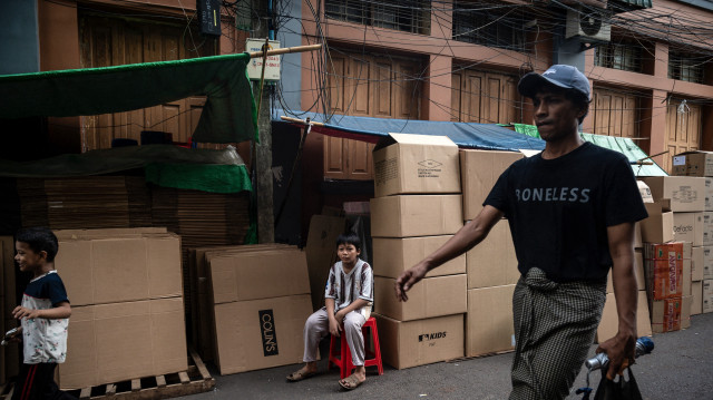 Un enfant attend des clients à l'extérieur d'un magasin vendant des boîtes en carton à Yangon, le 22 mai 2025.