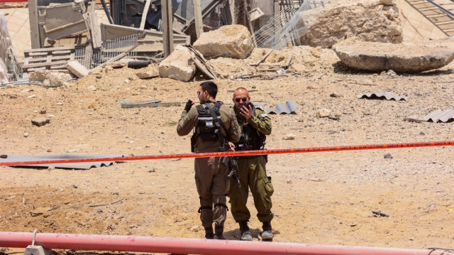 Des membres des forces de sécurité israéliennes se tiennent dans une zone bouclée sur le site d'impact d'une roquette iranienne près de la ville d'Ashdod, dans le sud du pays, le 23 juin 2025.