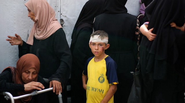 Un garçon palestinien blessé se tient parmi les personnes en deuil à l'hôpital des Martyrs d'al-Aqsa à Deir el-Balah, dans le centre de la bande de Gaza, le 1er juillet 2025.