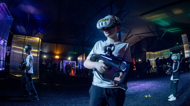 Des enfants tirent avec des pistolets en jouant à un jeu de réalité virtuelle à Plaza Gamer, un événement qui rassemble les développeurs et les fans de jeux vidéo, à Santiago, le 20 juin 2025.