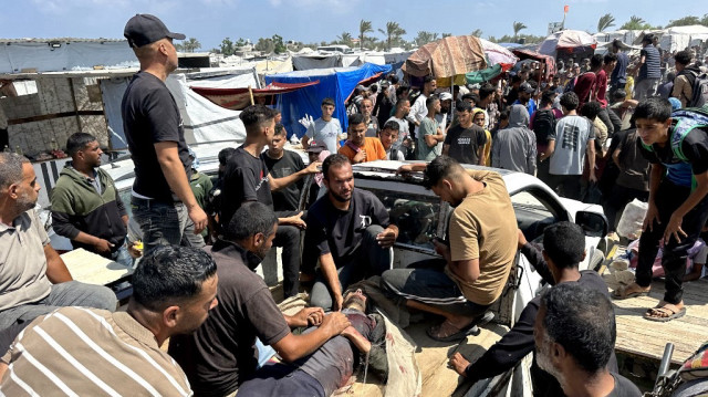 Des Palestiniens évacuent un blessé au milieu de longues files d'attente pour recevoir de l'aide humanitaire dans la ville de Rafah, au sud de Gaza, le 15 juin 2025.