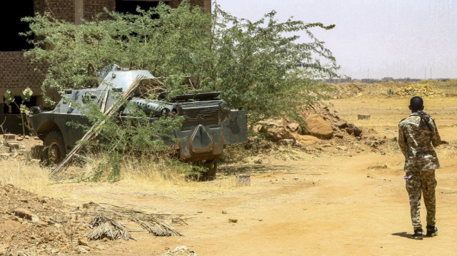 Un soldat de l'armée soudanaise marche près d'un véhicule blindé saisi après la prise d'une base utilisée par les forces paramilitaires rivales Rapid Support Forces (RSF), qui ont évacué la zone de Salha à Omdurman, la ville jumelle de la capitale soudanaise, le 26 mai 2025.